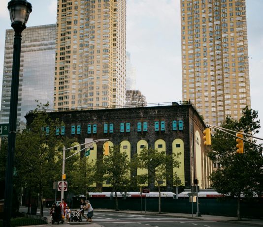 A vibrant intersection in Jersey City with towering skyscrapers and a historic building.