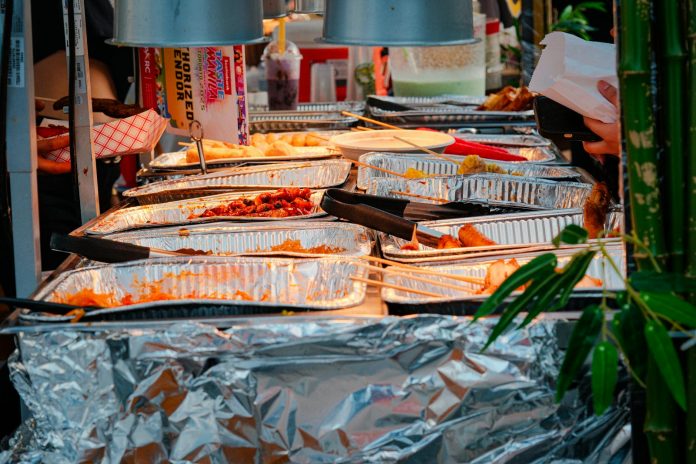 Explore a diverse range of delicious Asian street food at a bustling outdoor market stall.