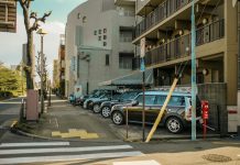 Jersey City rents drop as NYC costs surge A street view capturing parked cars alongside residential buildings on a sunlit day.
