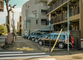 Jersey City rents drop as NYC costs surge A street view capturing parked cars alongside residential buildings on a sunlit day.