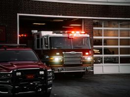 A fire truck exits the station, lights flashing, ready for emergency response.