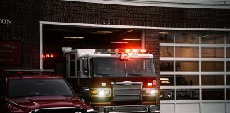 A fire truck exits the station, lights flashing, ready for emergency response.