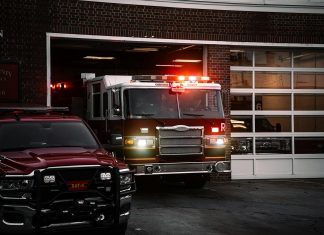 A fire truck exits the station, lights flashing, ready for emergency response.