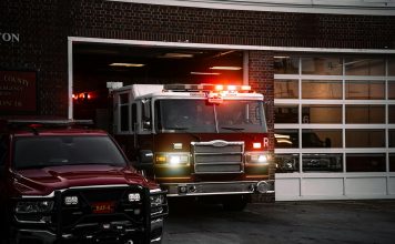 A fire truck exits the station, lights flashing, ready for emergency response.