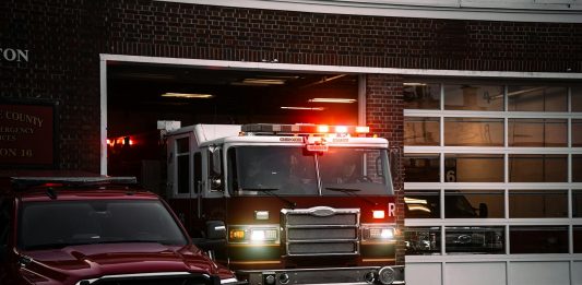 A fire truck exits the station, lights flashing, ready for emergency response.