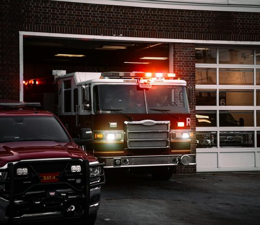 A fire truck exits the station, lights flashing, ready for emergency response.