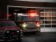 A fire truck exits the station, lights flashing, ready for emergency response.