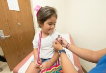 A cheerful young girl receives a band-aid after a vaccination at a clinic.