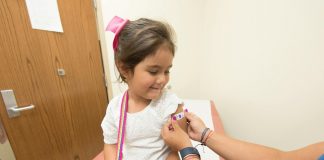 A cheerful young girl receives a band-aid after a vaccination at a clinic.