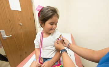 A cheerful young girl receives a band-aid after a vaccination at a clinic.