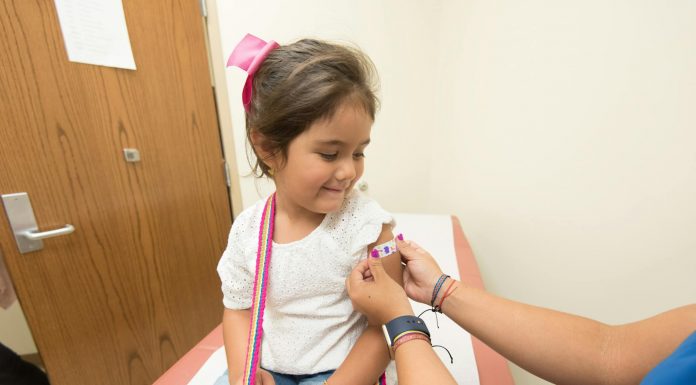 A cheerful young girl receives a band-aid after a vaccination at a clinic.