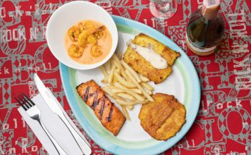 Delicious Colombian seafood platter featuring shrimp, fried plantains, and fish with a creamy sauce.