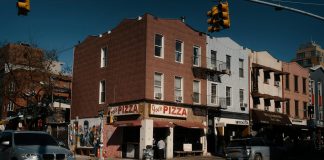Street view of Joe's Pizza on a sunny day in Brooklyn, showcasing the lively urban atmosphere.