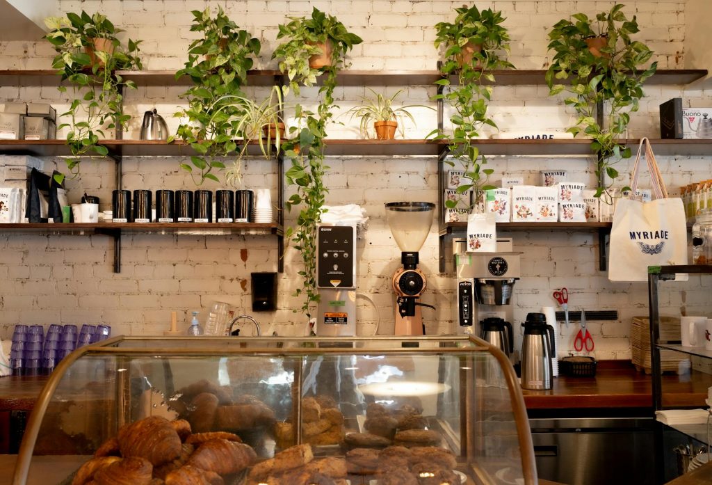 Inviting café in Montreal featuring a display of pastries and lush plants on shelves.