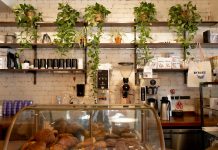 Inviting café in Montreal featuring a display of pastries and lush plants on shelves.