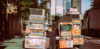 Colorful street food carts on a sunny New York City street offer a diverse culinary experience.