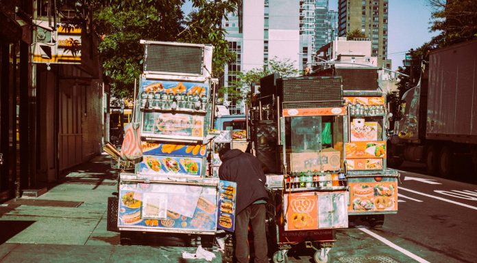 Colorful street food carts on a sunny New York City street offer a diverse culinary experience.