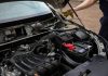 Mechanic inspecting car engine bay and battery during routine maintenance.