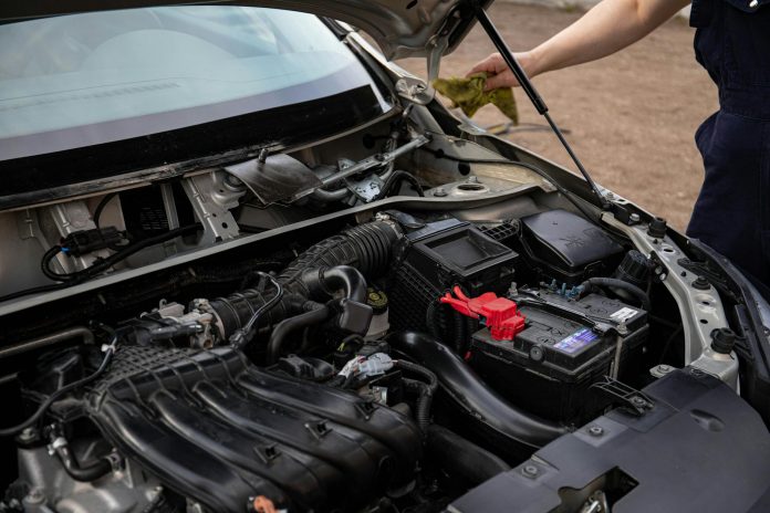 mejores-talleres-mecanicos-elizabeth Mechanic inspecting car engine bay and battery during routine maintenance.