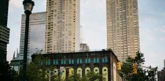 A vibrant intersection in Jersey City with towering skyscrapers and a historic building.