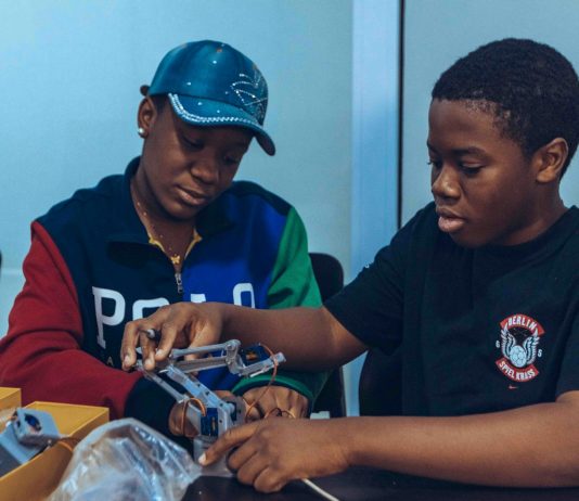 Two students assembling a robot in a hands-on STEM workshop in Accra, Ghana.