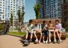 Children sitting on a bench, eating and sharing leisure time outdoors in a modern playground.