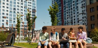 Los Mejores Programas Extraescolares en Jersey City para 2026: Guía Completa para Padres Children sitting on a bench, eating and sharing leisure time outdoors in a modern playground.