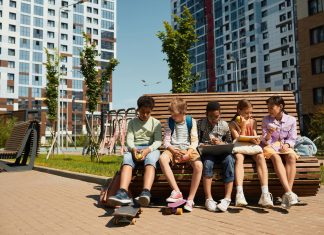 Los Mejores Programas Extraescolares en Jersey City para 2026: Guía Completa para Padres Children sitting on a bench, eating and sharing leisure time outdoors in a modern playground.