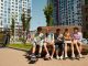 Children sitting on a bench, eating and sharing leisure time outdoors in a modern playground.