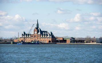 Pros and Cons of Living in Bayonne: A 2026 Local Guide Scenic view of the historic Ellis Island train station with clock tower set against a bright sky.