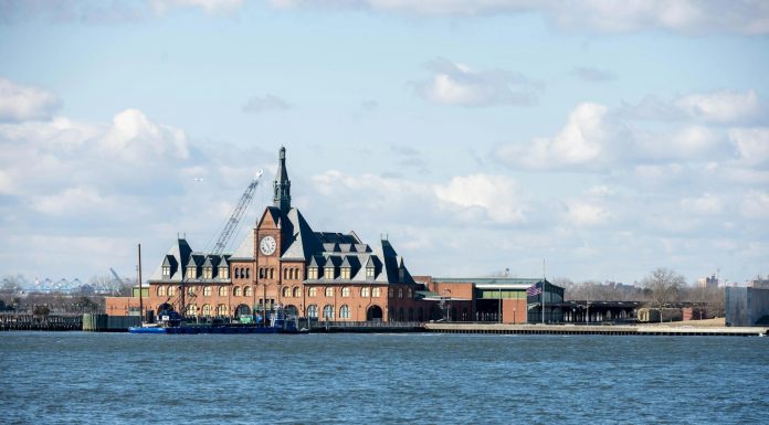 Scenic view of the historic Ellis Island train station with clock tower set against a bright sky.