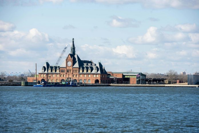 pros-and-cons-of-living-in-bayonne-2026 Scenic view of the historic Ellis Island train station with clock tower set against a bright sky.