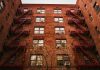 View of iconic red brick apartments with fire escapes in New York.