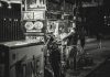 Black and white photo of a food vendor in New York City, capturing urban night life.