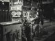 Black and white photo of a food vendor in New York City, capturing urban night life.