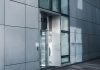 Sleek modern architecture featuring a glass entrance with reflective facade, showcasing contemporary design.