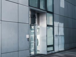 Sleek modern architecture featuring a glass entrance with reflective facade, showcasing contemporary design.