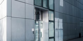 Sleek modern architecture featuring a glass entrance with reflective facade, showcasing contemporary design.