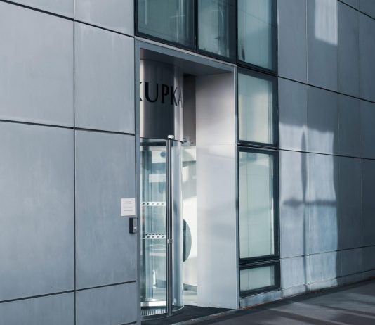 Sleek modern architecture featuring a glass entrance with reflective facade, showcasing contemporary design.