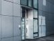 Sleek modern architecture featuring a glass entrance with reflective facade, showcasing contemporary design.
