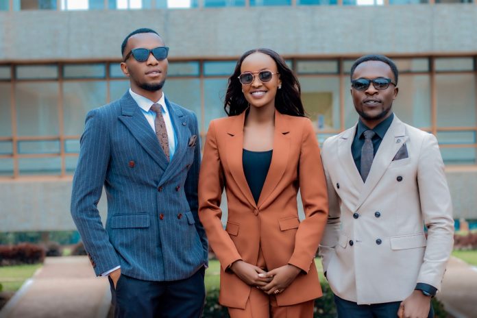 Three young professionals in stylish suits posing confidently outdoors.