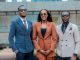 Three young professionals in stylish suits posing confidently outdoors.