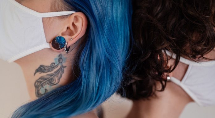Bayonne police identify suspect in $60K jewelry store armed robbery Two women back to back wearing face masks, showcasing tattoos and colorful hair.