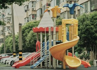 Vibrant playground with slides and equipment in an urban park setting surrounded by apartment buildings.