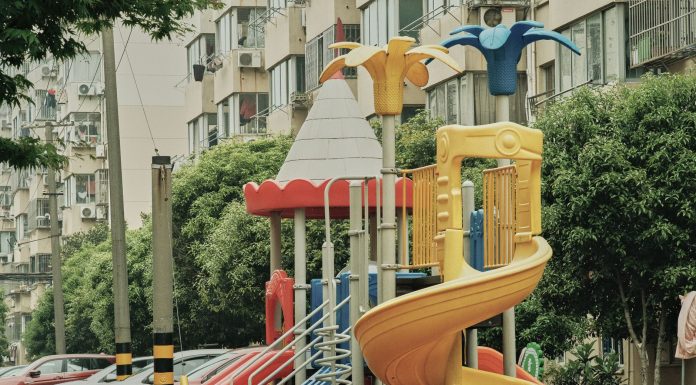 Vibrant playground with slides and equipment in an urban park setting surrounded by apartment buildings.