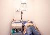 Patient lying down for an electrocardiogram in a clinic room wearing a face mask.