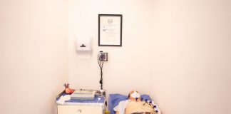 Patient lying down for an electrocardiogram in a clinic room wearing a face mask.