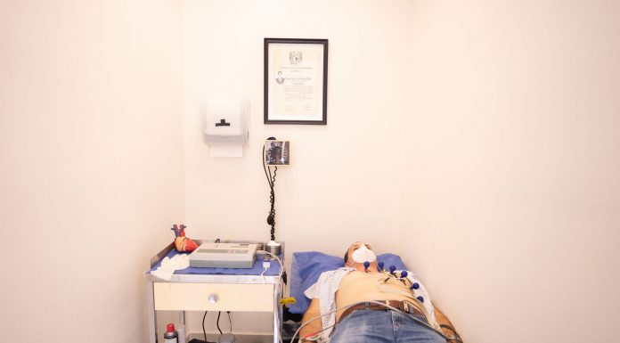 Patient lying down for an electrocardiogram in a clinic room wearing a face mask.