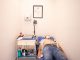 Patient lying down for an electrocardiogram in a clinic room wearing a face mask.
