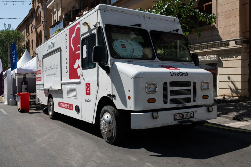 White food truck by LiveChef at a bustling street festival under sunny skies.
